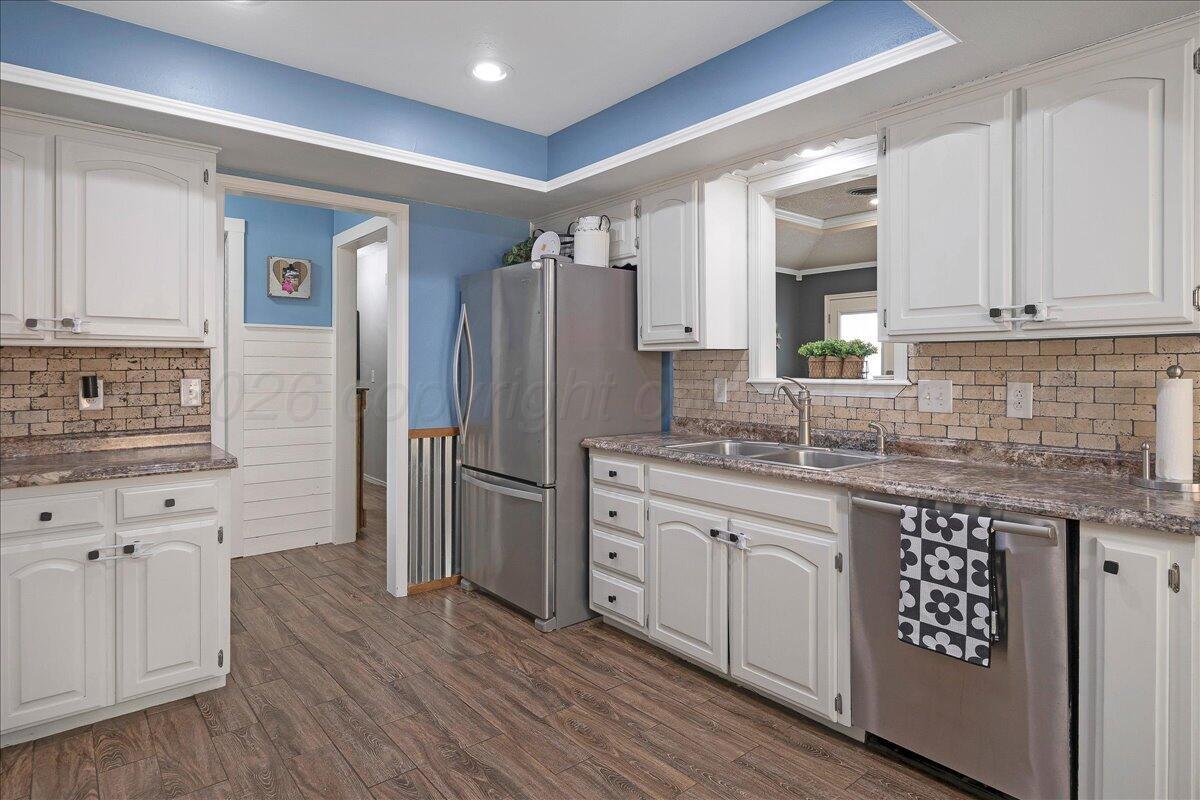 6912 Manor Circle Amarillo, TX 79109 - Photo 9 of 25 a kitchen with stainless steel appliances granite countertop a refrigerator a sink and white cabinets