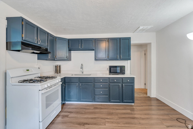358 400 South Provo, UT 84601 - Photo 2 of 34 Kitchen with white range with gas cooktop, light wood finished floors, blue cabinetry.