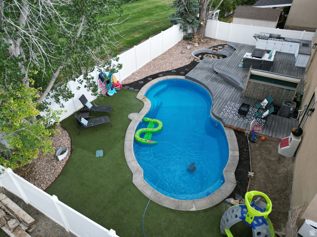 1585 South 910 West Payson, UT 84651 - Photo 29 of 32 Backyard oasis featuring a custom-shaped swimming pool with stone coping, a multi-level composite deck, an integrated outdoor kitchen, and a circular fire pit area