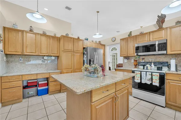 a kitchen with kitchen island granite countertop a sink cabinets and stainless steel appliances