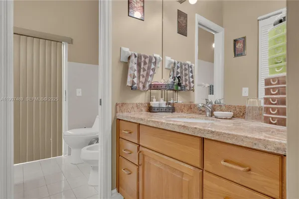 a bathroom with a granite countertop sink mirror and a toilet