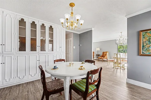 a dining room with wooden floor a chandelier a wooden table and chairs