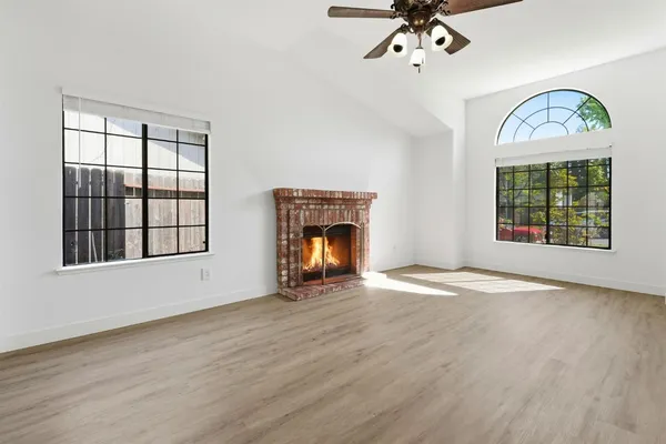 an empty room with windows fireplace and wooden floor