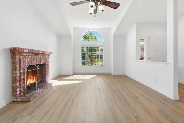 an empty room with windows fireplace and wooden floor