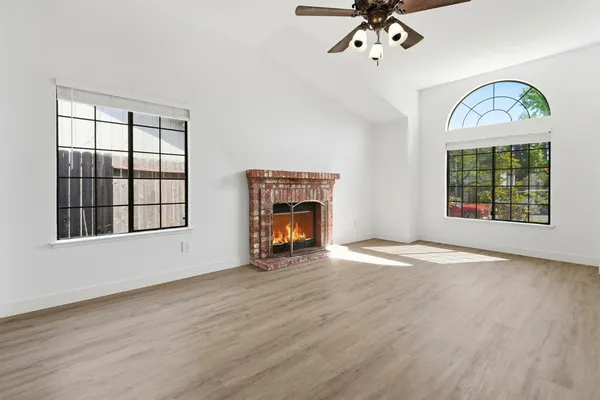 an empty room with windows fireplace and wooden floor