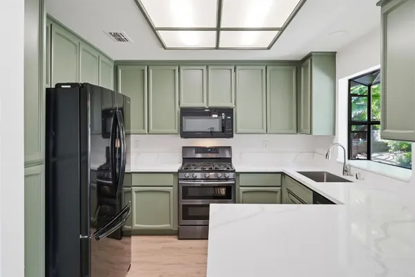 a kitchen with granite countertop a refrigerator and a stove top oven
