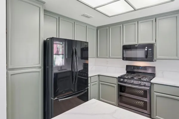 a kitchen with granite countertop a refrigerator and a stove top oven