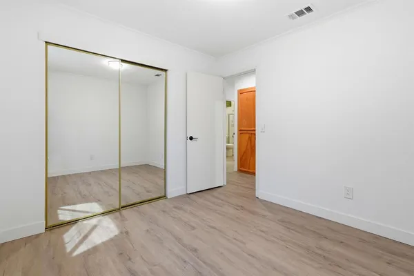 a view of an empty room with wooden floor and closet
