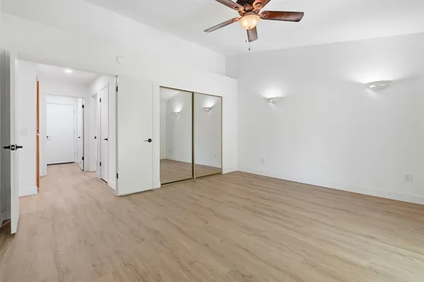 an empty room with wooden floor and fan
