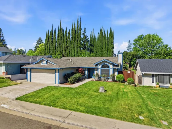 a front view of a house with a garden and trees