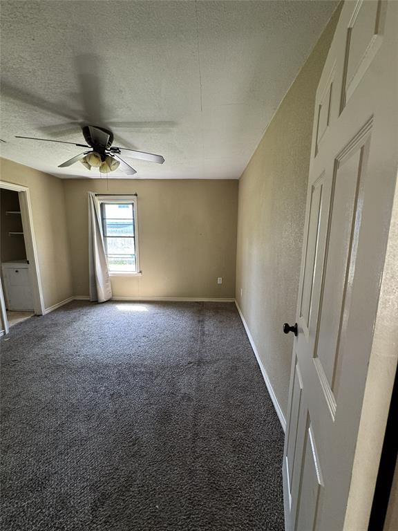 803 Ripley Avenue Ennis, TX 75119 - Photo 23 of 40 Spacious room featuring neutral wall tones, dark carpeting, and a ceiling fan with integrated lighting