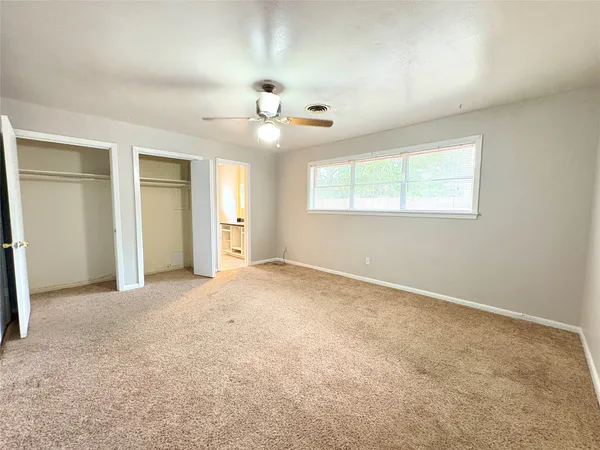 an empty room with windows and ceiling fan