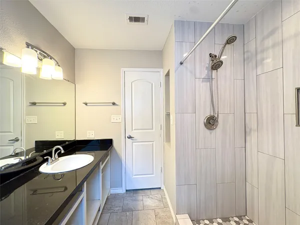 a bathroom with a granite countertop sink tub shower and a mirror