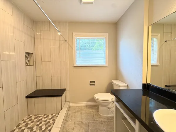 a bathroom with a granite countertop sink toilet and shower