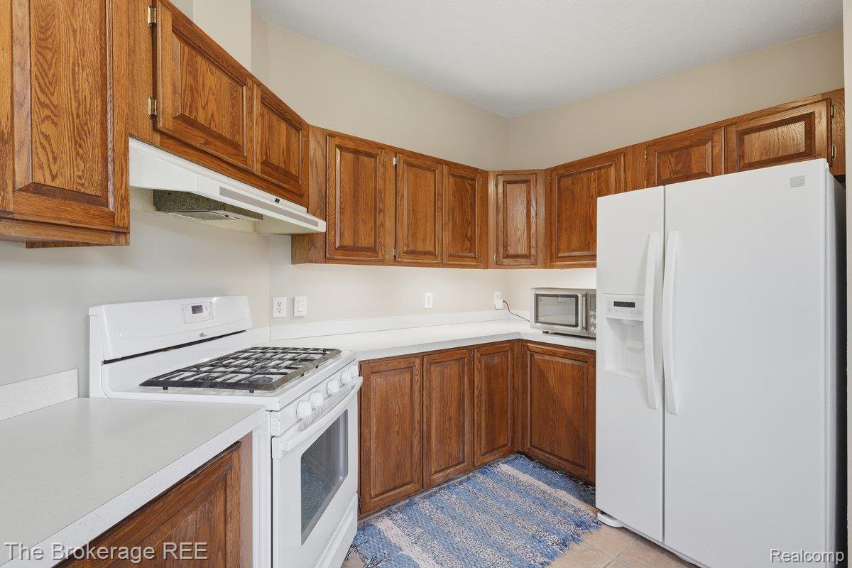 2422 South Henderson Road Davison, MI 48423 - Photo 24 of 53 Kitchen featuring wood cabinetry, white countertops, a white gas range, and a white side-by-side refrigerator