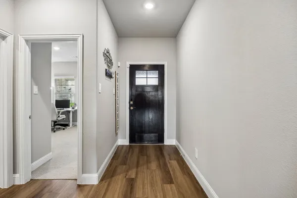 a view of a hallway with wooden floor and a bathroom