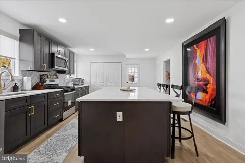 a kitchen with stainless steel appliances granite countertop a sink a stove a refrigerator cabinets and a dining table