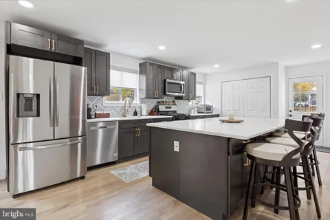 a kitchen with stainless steel appliances granite countertop a refrigerator a stove a sink a dining table and chairs