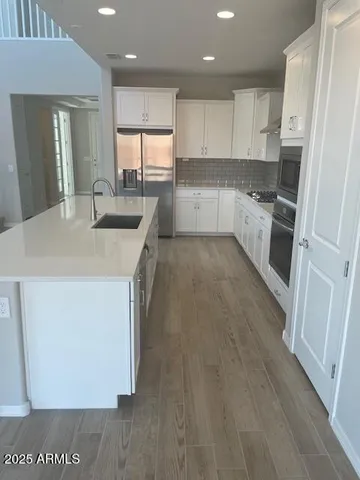 a kitchen with a sink a stove a refrigerator and white cabinets