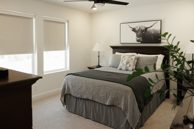 629 Spring Lily Drive St. George, UT 84790 - Photo 24 of 50 Bedroom featuring a dark wood headboard, two windows with roller shades, a ceiling fan with integrated lighting, and neutral carpeting