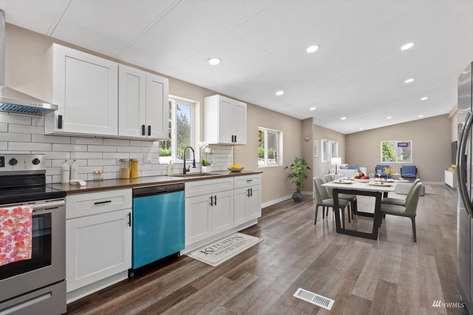 a kitchen with counter space wooden floor dining table and stainless steel appliances