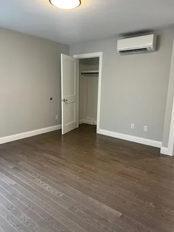 a view of an empty room with wooden floor and closet