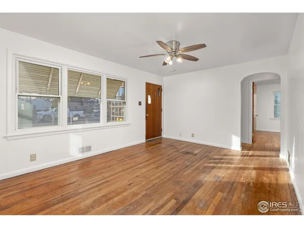a view of empty room with wooden floor and fan