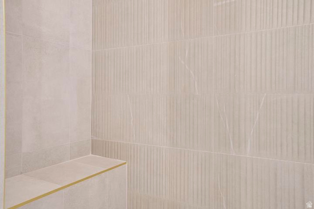 990 Manen Street Washington, UT 84780 - Photo 22 of 43 Shower enclosure featuring a built-in bench, smooth light-toned tile, and textured vertical-groove accent tile