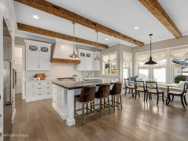 a kitchen with stainless steel appliances a dining table chairs stove and wooden floor