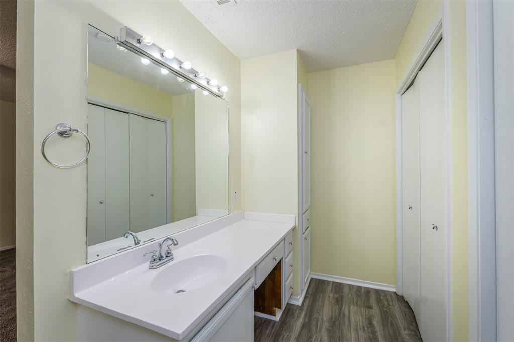 617 Rolling Ridge Court Azle, TX 76020 - Photo 10 of 20 Bathroom vanity featuring a large mirror with strip lighting, a white countertop with an integrated sink, and wood-finish flooring