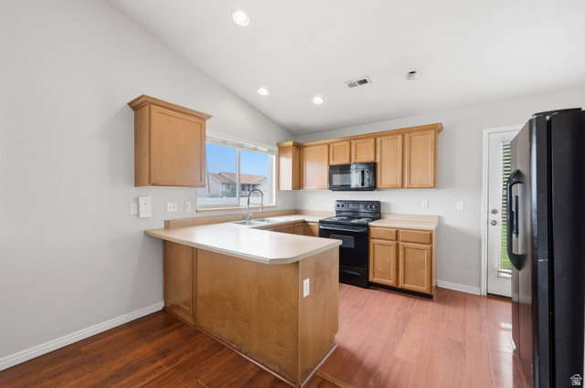 2575 Athena Drive Magna, UT 84044 - Photo 6 of 23 Kitchen featuring wood-finish flooring, light wood cabinetry, light-toned countertops, a stainless steel sink, and black appliances