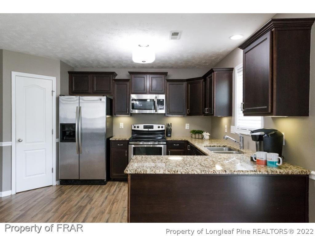 664 Cape Fear Road Raeford, NC 28376 - Photo 8 of 36 a kitchen with stainless steel appliances granite countertop a refrigerator a sink a stove a microwave and wooden cabinets