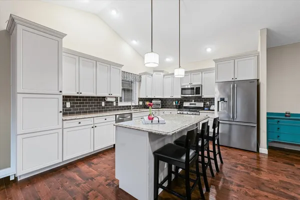 a kitchen with stainless steel appliances kitchen island a table chairs refrigerator and microwave