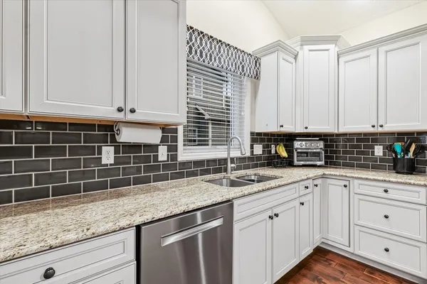 a kitchen with granite countertop a sink a stove and cabinets