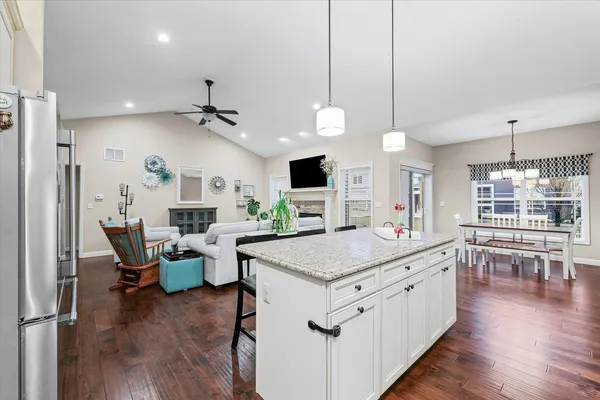 a open kitchen with stainless steel appliances granite countertop a stove and chairs with wooden floor