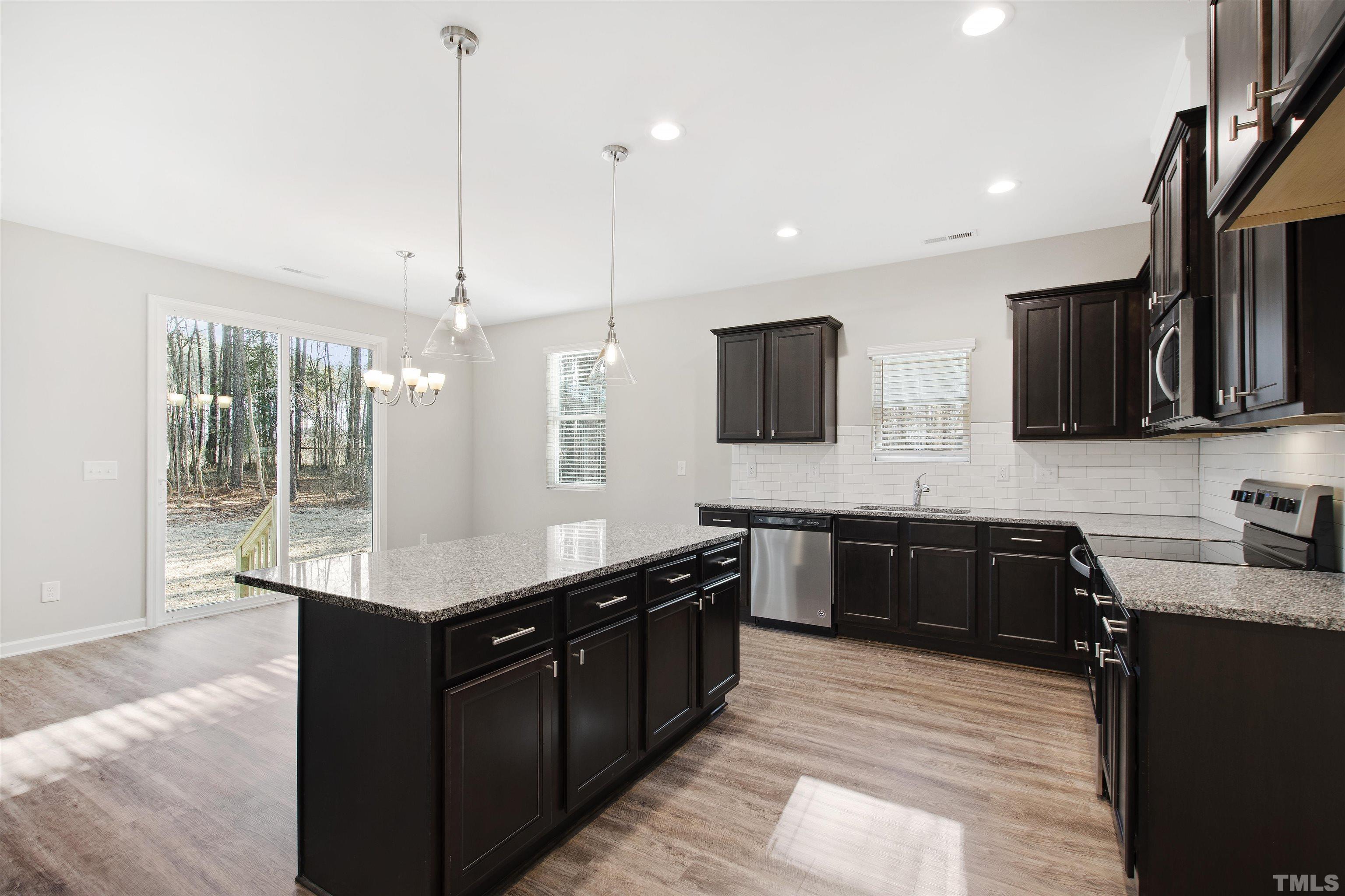 a kitchen with stainless steel appliances granite countertop a sink a stove and a wooden floor