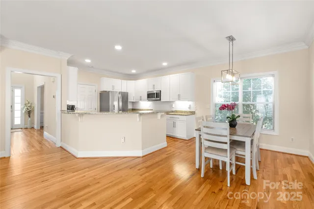 a view of a dining room and livingroom with furniture wooden floor a chandelier
