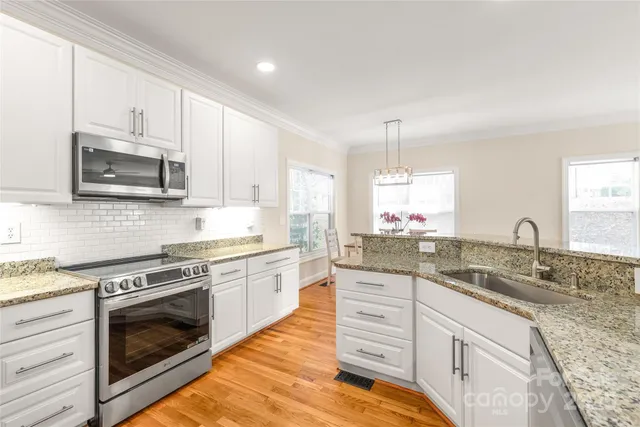 a kitchen with granite countertop a sink stainless steel appliances and cabinets