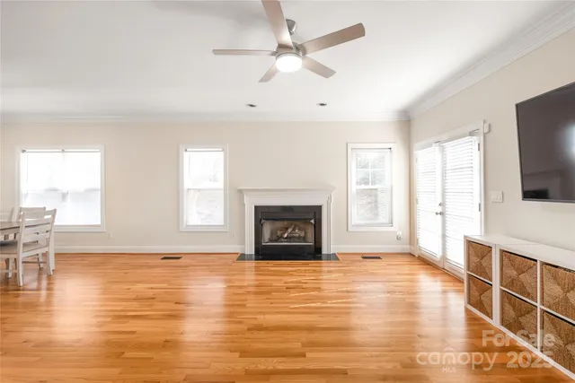 a view of a livingroom with a fireplace a ceiling fan and wooden floor