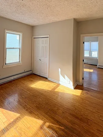 a view of an empty room with window and wooden floor