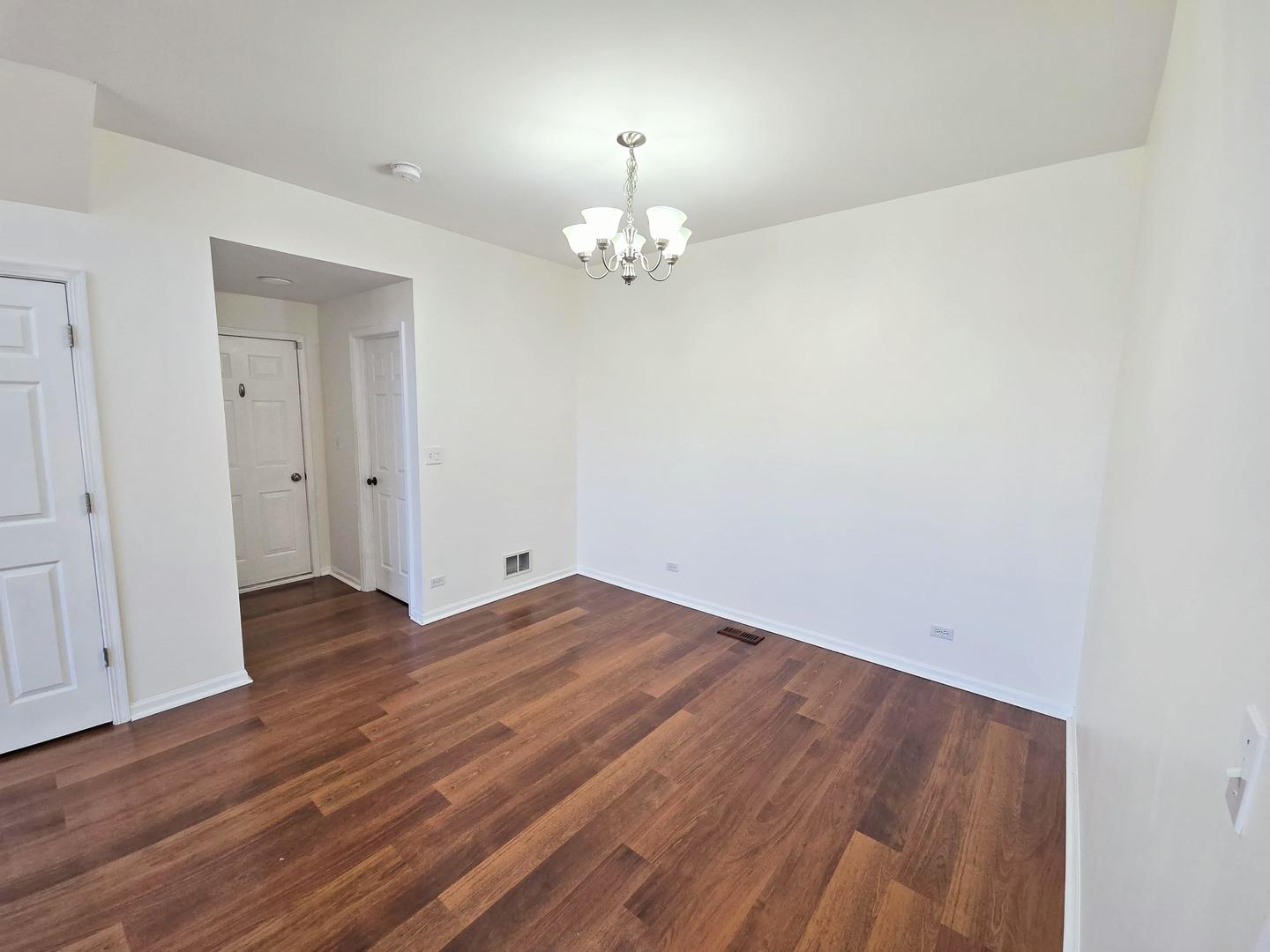 2028 Cypress Court Glendale Heights, IL 60139 - Photo 17 of 25 an empty room with wooden floor chandelier and windows