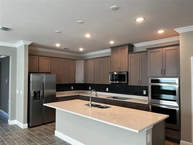 a kitchen with granite countertop a refrigerator and a stove top oven