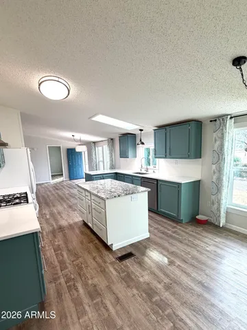 a large white kitchen with kitchen island a sink dishwasher stove with wooden floor and cabinets