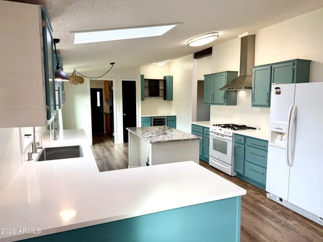 a large white kitchen with sink a refrigerator and white cabinets