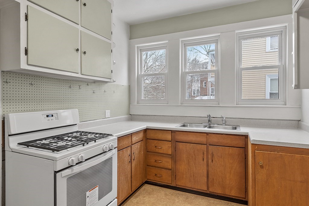 42 Radnor Road Boston, MA 02135 - Photo 12 of 17 a kitchen with granite countertop cabinets sink stove and window