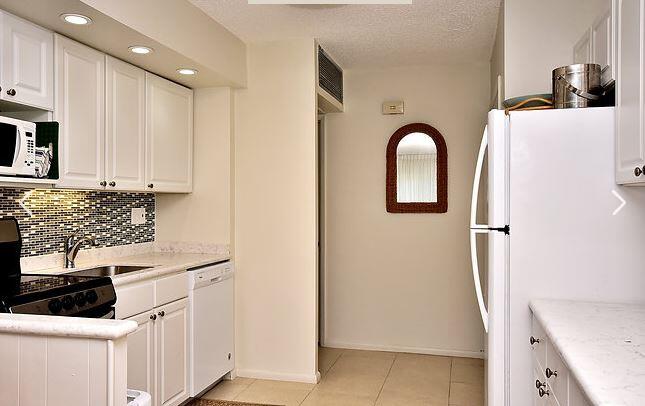150 North Ocean Boulevard, Unit S26 Delray Beach, FL 33483 - Photo 4 of 8 a kitchen with a refrigerator and cabinets