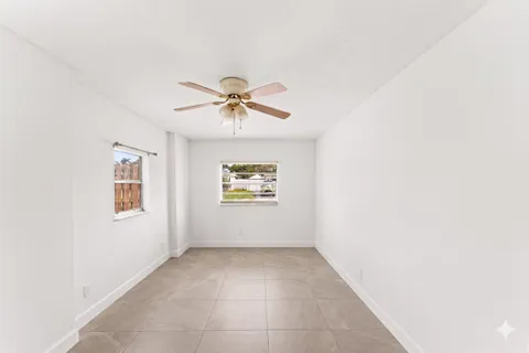 an empty room with windows and fan