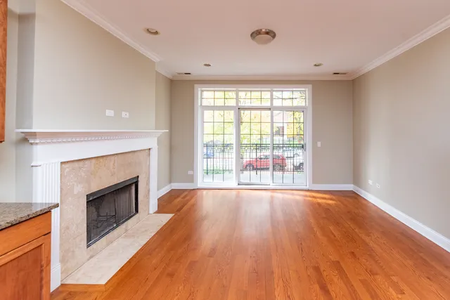 a view of an empty room with wooden floor fireplace and a window