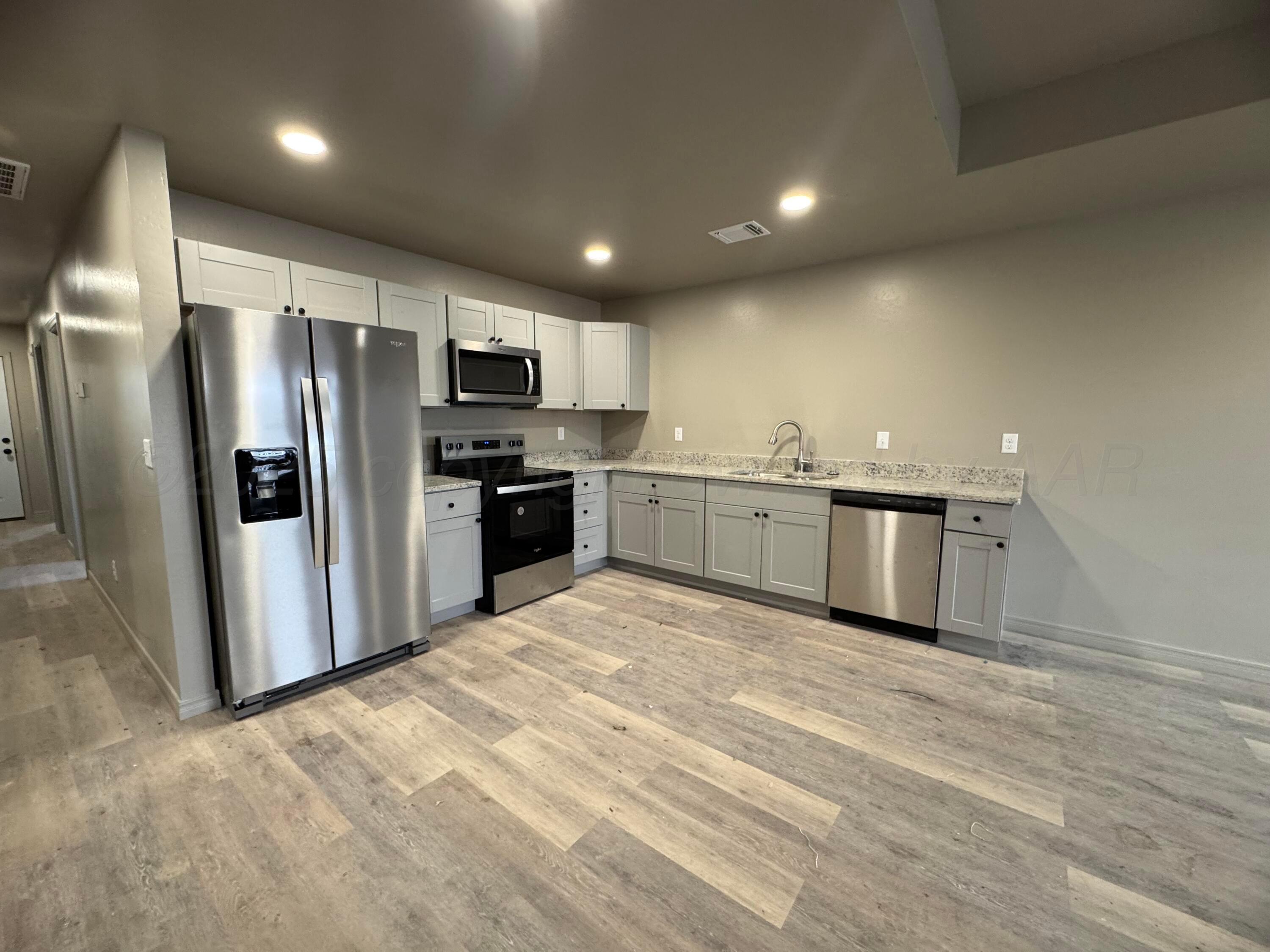 1112 Caprock Street Hereford, TX 79045 - Photo 3 of 10 a kitchen with stainless steel appliances granite countertop a refrigerator and a sink