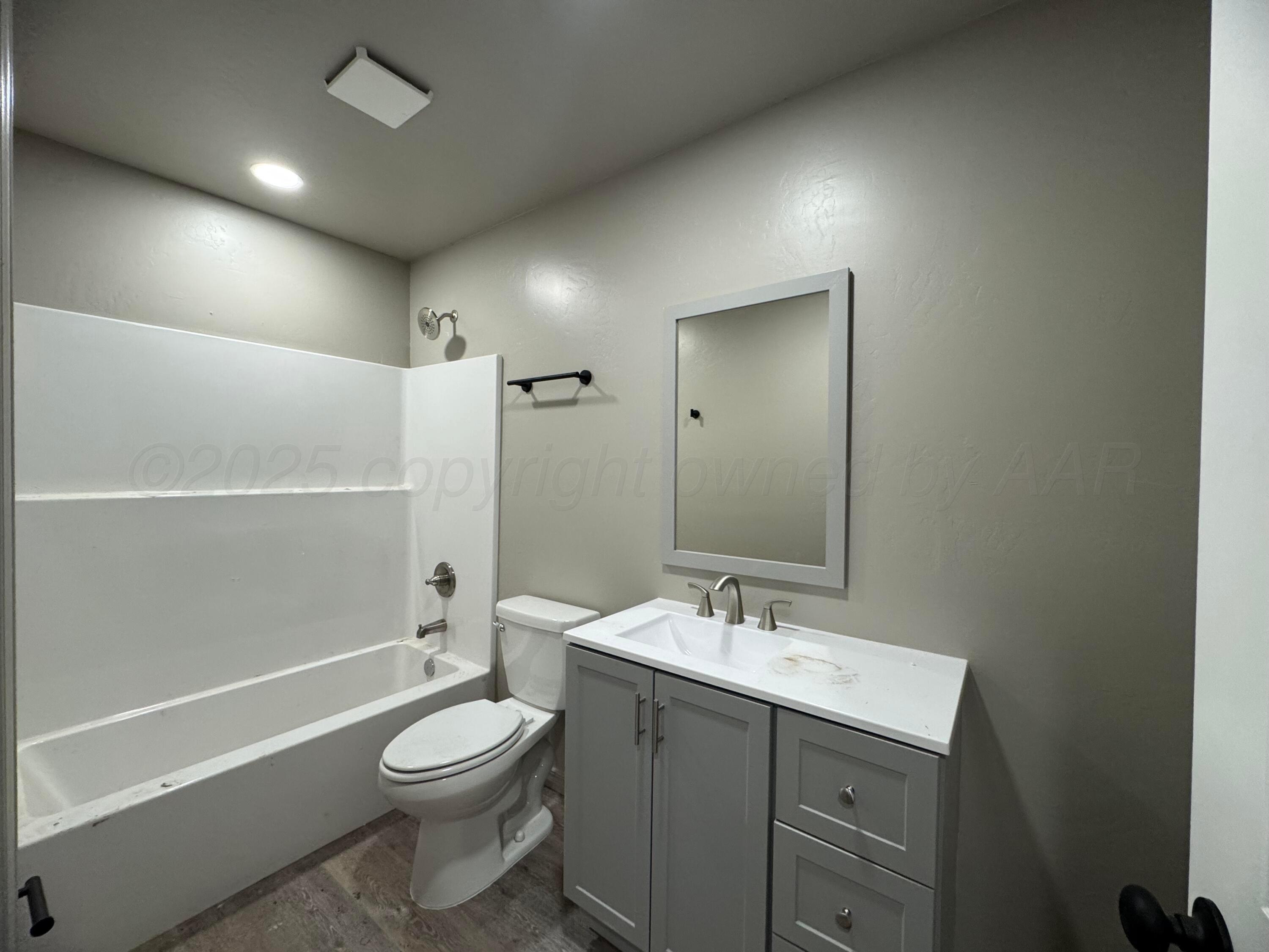 1112 Caprock Street Hereford, TX 79045 - Photo 5 of 10 a bathroom with a toilet a sink a mirror and a bathtub